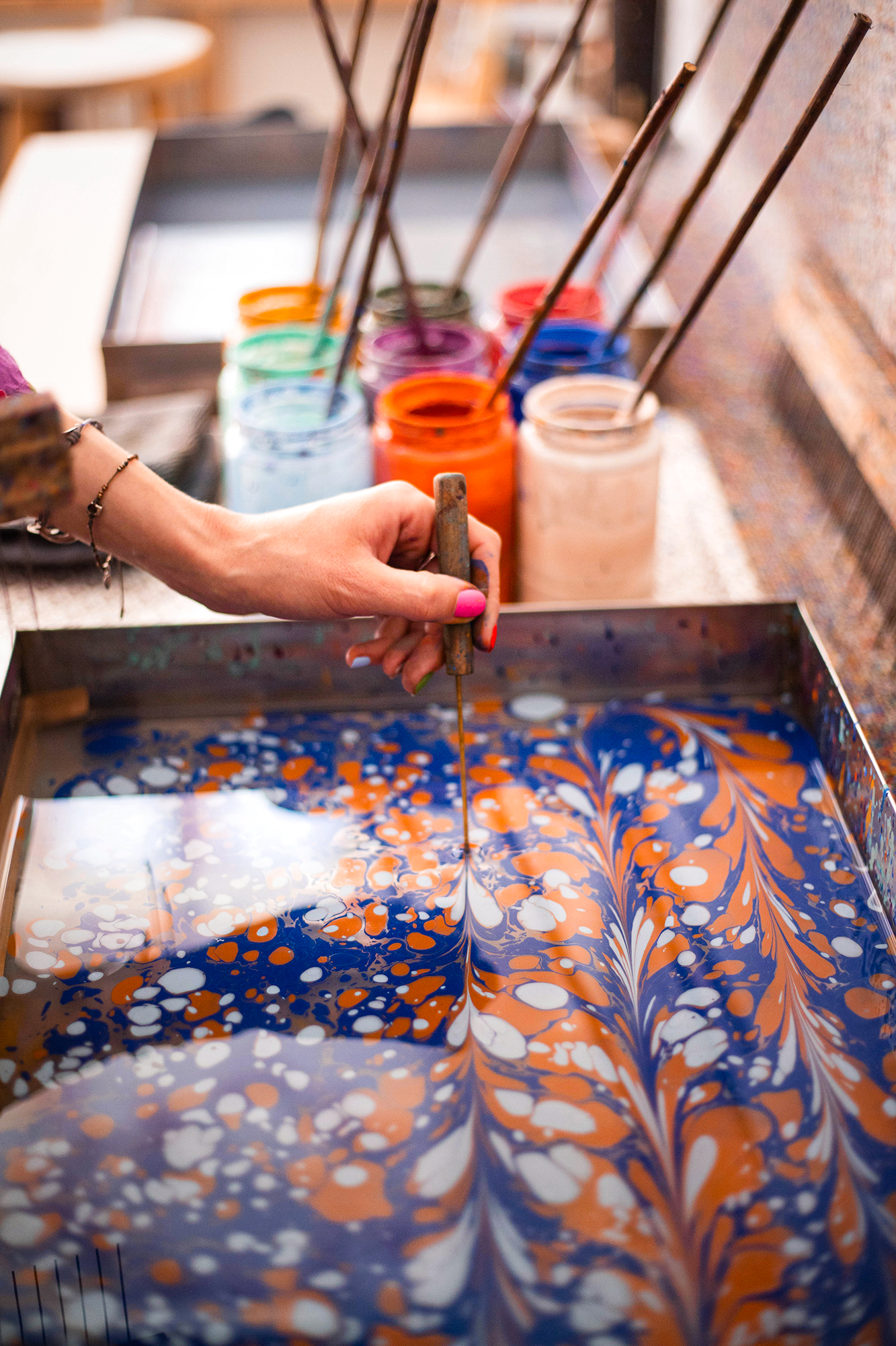 Marbrure sur eau en cours, pigments bleus et orangés sur le bain